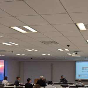 日本美容医療協会総会セミナーで講演する柏崎氏の様子。会議室で参加者が着席し、前方のスクリーンにはプレゼンテーション資料が表示されている